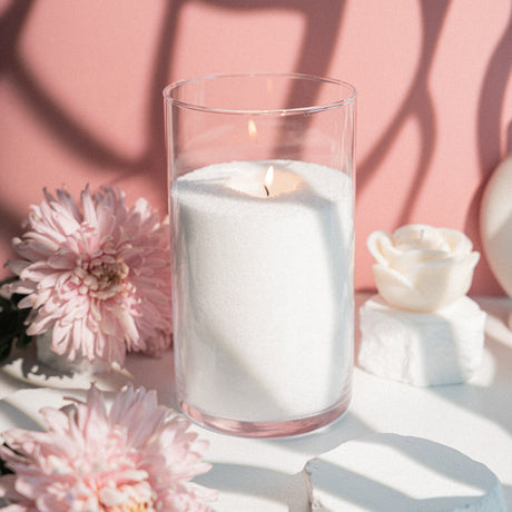 Tīrs, balts beramais sveču vasks stikla traukā ar degošu liesmu