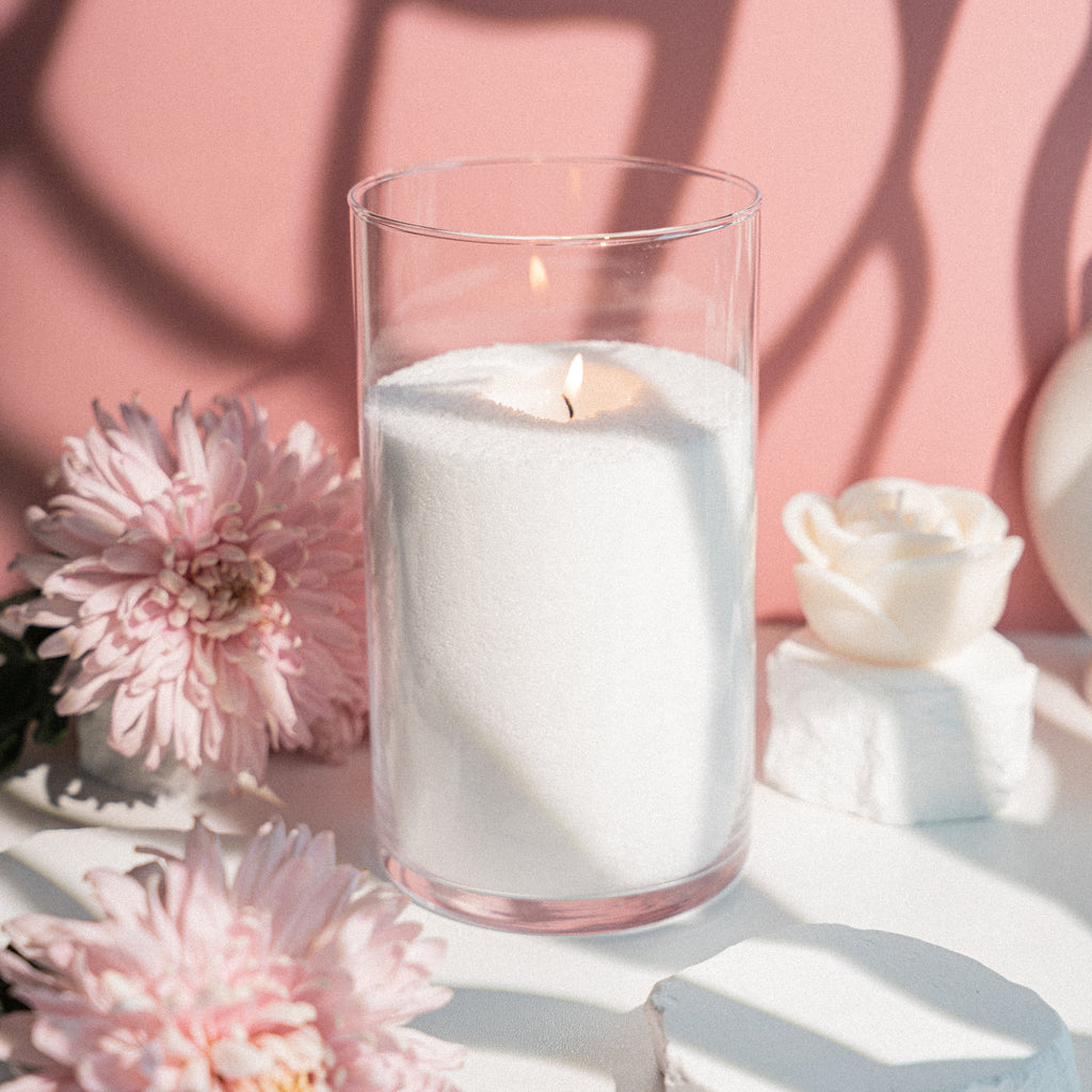 Tīrs, balts beramais sveču vasks stikla traukā ar degošu liesmu