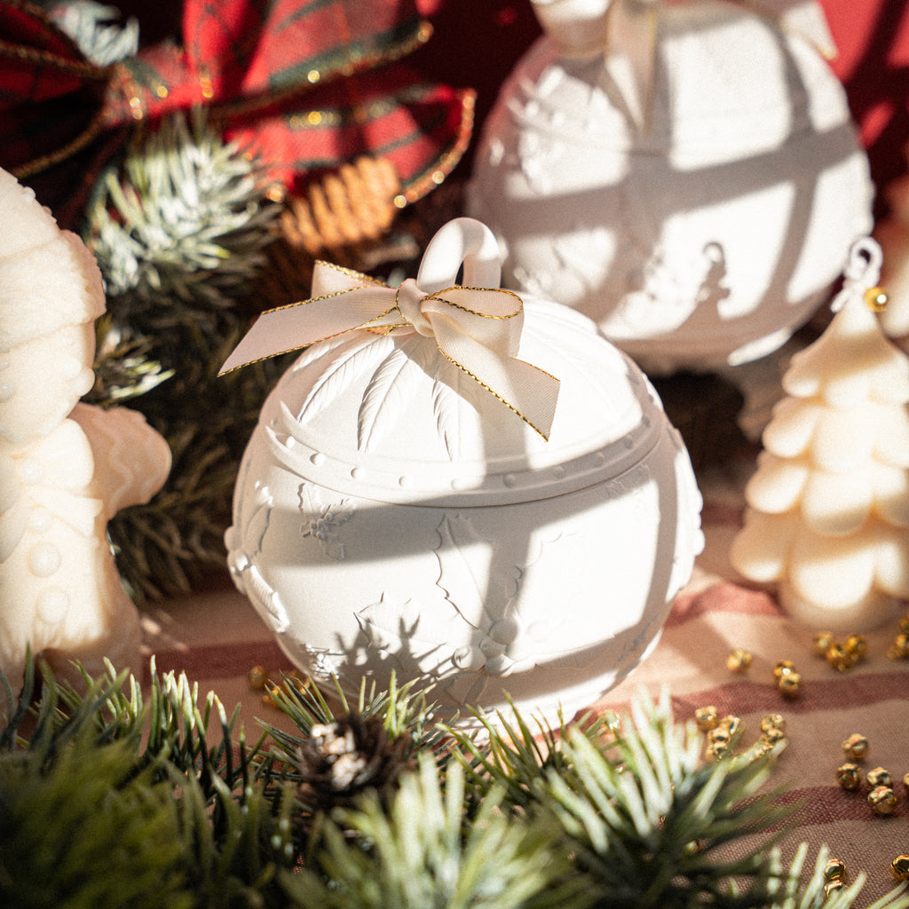 White handmade Christmas ornament candle jar with festive ribbon and greenery