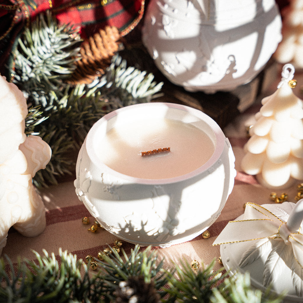 Handmade Christmas candle in white jar, surrounded by pine branches and festive accents
